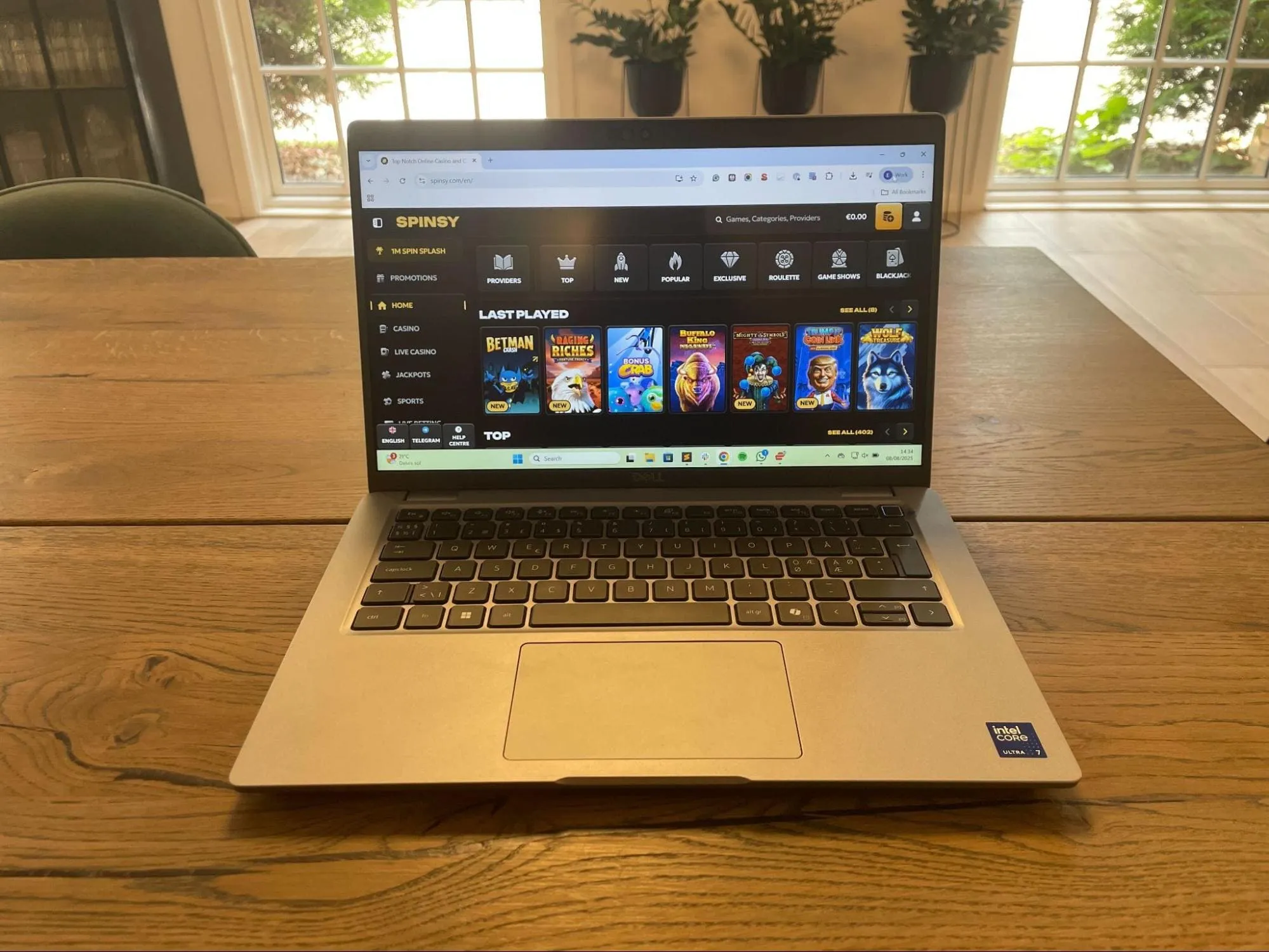 Open laptop on a desk showing Spinsy casino site with jackpot slot categories and game thumbnails visible.